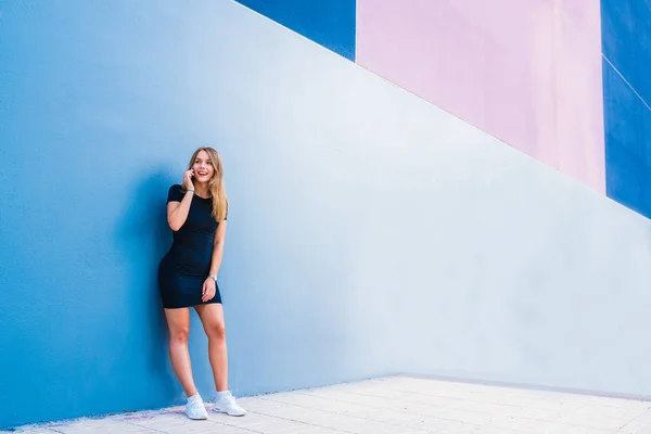 Glückliche junge Frau am Handy an einer bunten Wand — Stockfoto