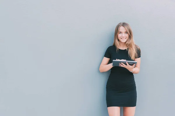 Šťastná mladá žena na tabletu u zdi — Stock fotografie