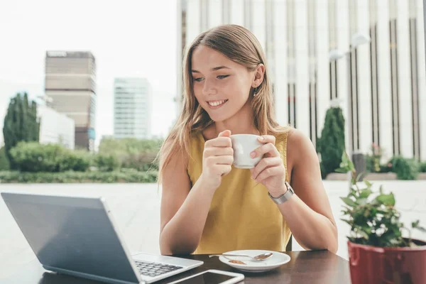 Молодая деловая женщина за компьютером пьет кофе — стоковое фото