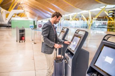mutlu adam havaalanında biniş kartı almak check-in makinesini kullanarak.