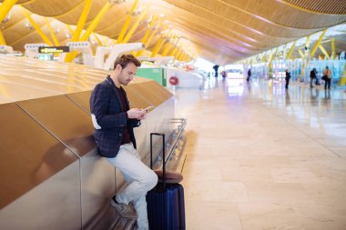 Havaalanında bekliyor ve kullanma cep telefonu genç adam 