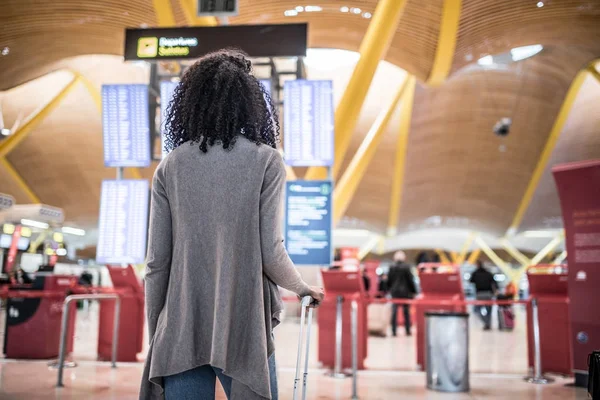 女性がスーツケースを持って空港の時刻表情報パネルを見て — ストック写真