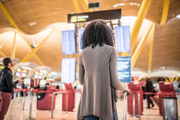 Femme regardant le panneau d'information horaire à l'aéroport avec une valise — Photo
