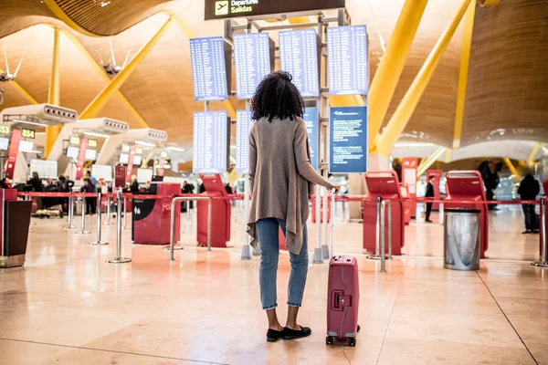 Femme regardant le panneau d'information horaire à l'aéroport avec une valise — Photo