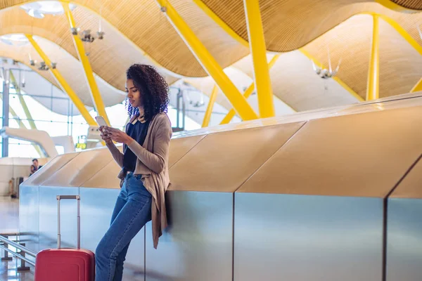 Schwarze Frau wartet mit Handy am Flughafen auf ihren Flug — Stockfoto