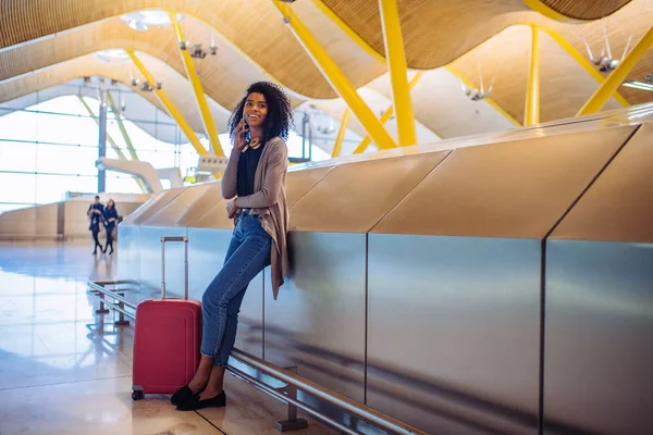 Frau wartet am Flughafen mit Handy auf ihren Flug — Stockfoto