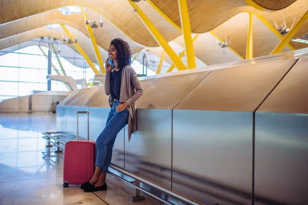 Schwarze Frau wartet mit Handy am Flughafen auf ihren Flug — Stockfoto