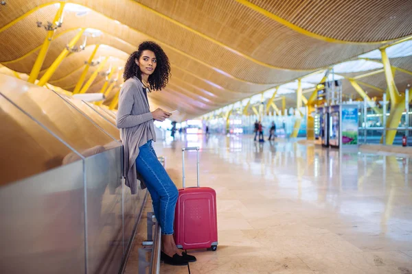 Schwarze Frau wartet mit Handy am Flughafen auf ihren Flug — Stockfoto