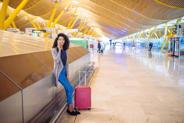 Mujer negra esperando su vuelo usando teléfono móvil en el aeropuerto — Foto de Stock