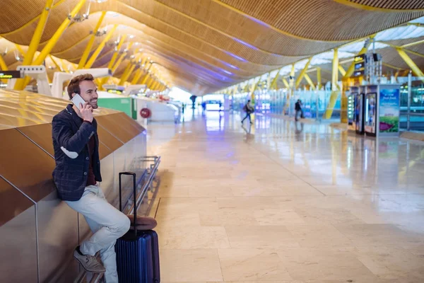 Joven que espera y utiliza el teléfono móvil en el aeropuerto — Foto de Stock