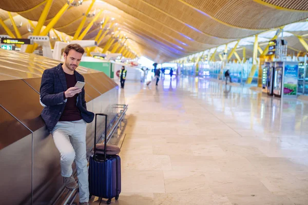 Mladý muž čekal a pomocí mobilního telefonu na letišti — Stock fotografie