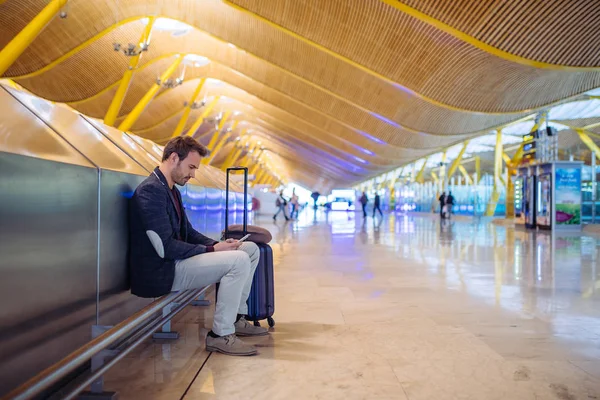 Young man waiting and using mobile phone at the airport — Stock Photo, Image