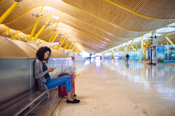 Jeune femme heureuse écoutant de la musique avec écouteurs et téléphone portable à l'aéroport — Photo