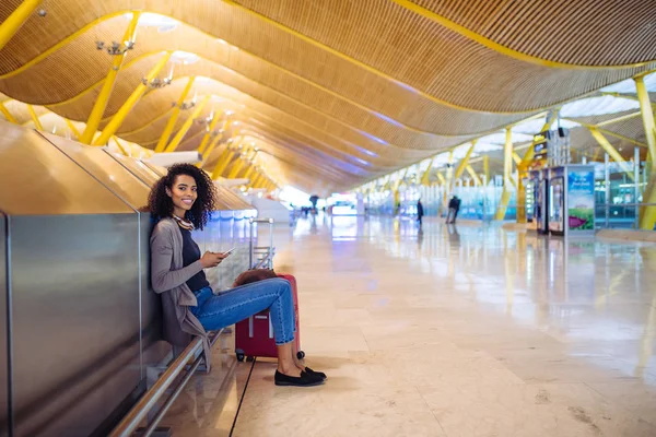 Jeune femme heureuse écoutant de la musique avec écouteurs et téléphone portable à l'aéroport — Photo