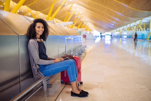 Glückliche junge Frau, die am Flughafen mit Kopfhörer und Handy Musik hört — Stockfoto