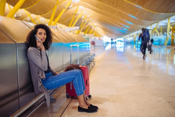 Glückliche junge Frau, die am Flughafen mit Kopfhörer und Handy Musik hört — Stockfoto