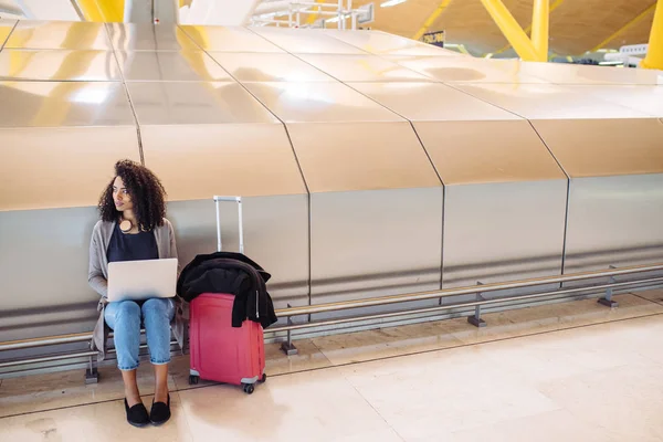 Atraente preto mulher no aeroporto sentado e trabalhando com laptop — Fotografia de Stock