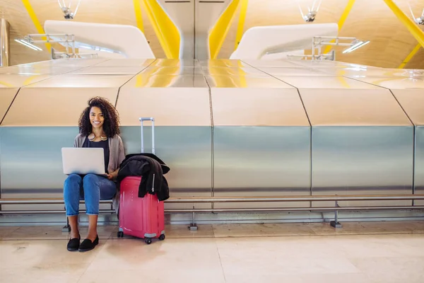 çekici siyah kadın havaalanında oturuyor ve laptop ile çalışma