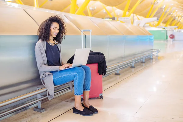 Atractiva mujer en el aeropuerto sentado y trabajando con el ordenador portátil — Foto de Stock