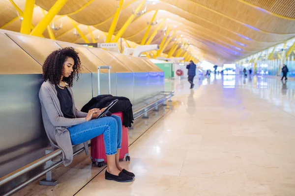 태블릿을 사용 하 여 헤드폰으로 음악을 듣고 공항에서 여자 — 스톡 사진