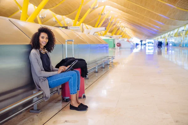 Frau am Flughafen benutzt Tablet und hört Musik über Kopfhörer — Stockfoto