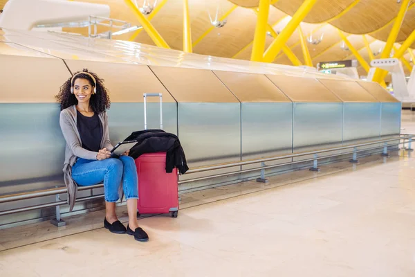 Kadın havaalanında tablet kullanma ve kulaklık ile müzik dinleme