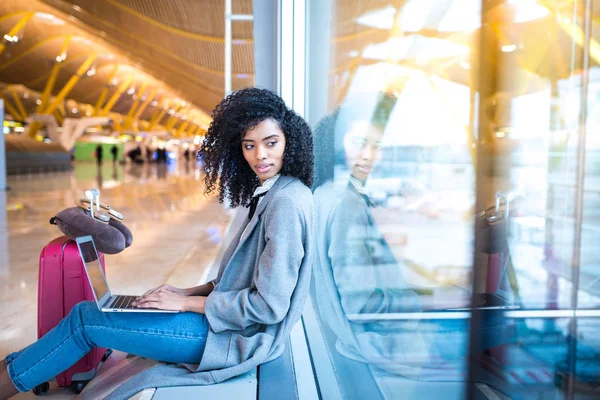 Donna nera che lavora con il computer portatile in aeroporto in attesa alla finestra — Foto Stock