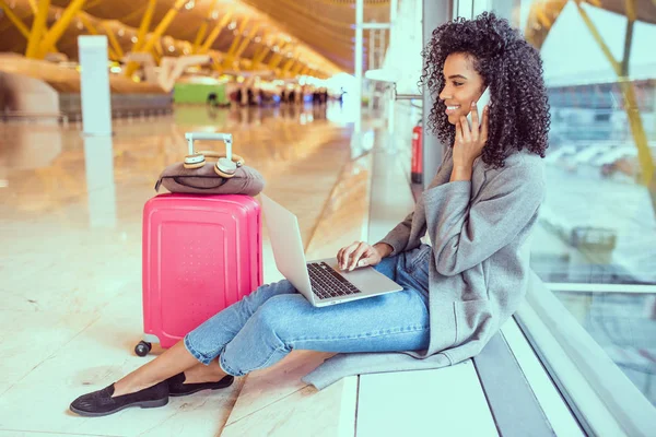 Mujer usando teléfono móvil y portátil en el aeropuerto sentado en la ventana — Foto de Stock