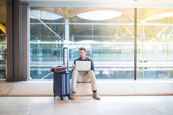 Man sitting at the airport using laptop and mobile phone next to the window. — Stock Photo, Image