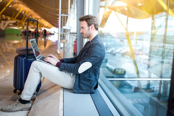 Man sitting at the airport using laptop and mobile phone next to the window. — Stock Photo, Image