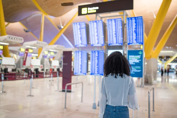 Femme regardant le panneau d'information horaire à l'aéroport avec une valise — Photo