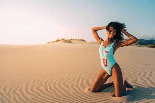 Vacker ung kvinna poserar på sanden i en öken sanddyner — Stockfoto