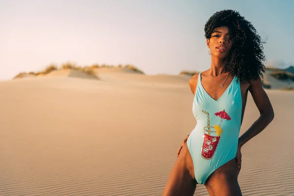 Beautiful young woman posing on the sand in a desert dunes — Stock Photo, Image