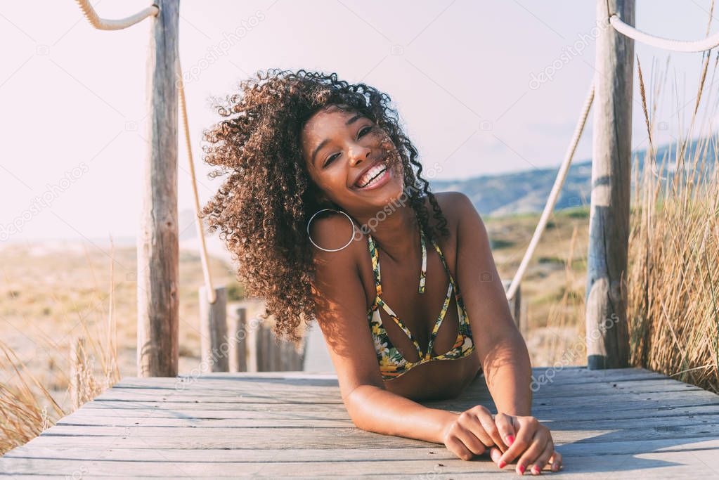 Beautiful young black woman lying down in a  wooden foot bridge 