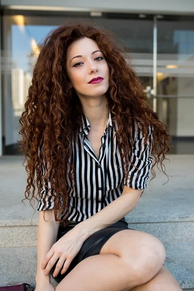 Young redhead business woman sitting on the stairs