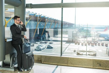 onun uçuş havaalanında kapatmak için terminal penceresi yakışıklı işadamı ayakta bekliyor