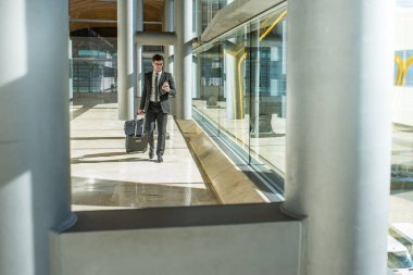 genç işadamı havaalanında cep telefonunu kullanarak yürüyüş