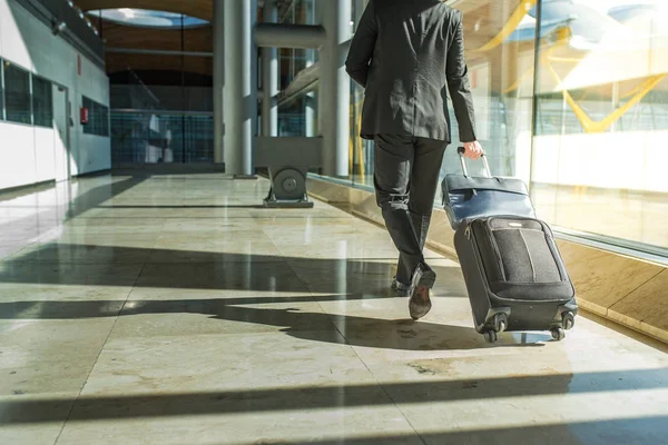 businessman back and legs walking with luggage at the airport