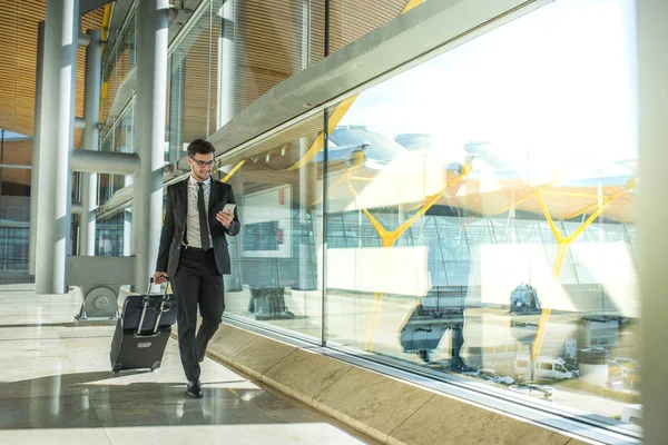 Młody Biznesmen Chodzenie Lotnisku Pomocą Swojego Telefonu Komórkowego — Zdjęcie stockowe