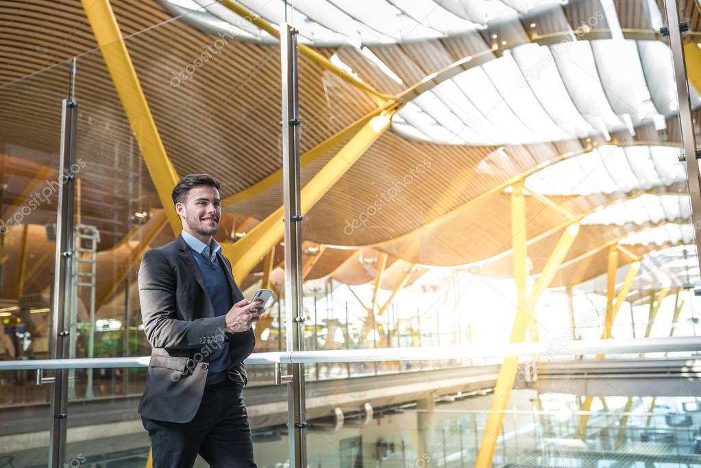 young attractive man walking at the airport using his mobile phone 