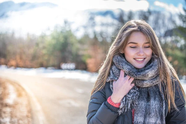 Jeune jolie femme sur une route enneigée en hiver — Photo