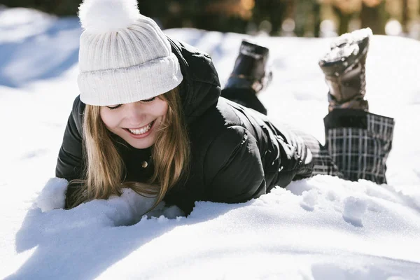 Ung söt kvinna liggande spelar och njuter av snö i vinter — Stockfoto