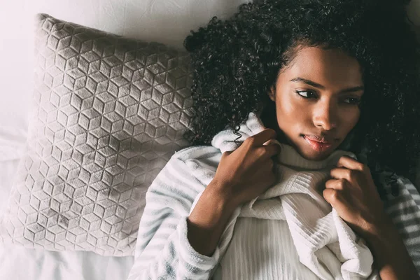 Όμορφη στοχαστικό μαύρη γυναίκα με σγουρά μαλλιά ξαπλωμένος στο κρεβάτι που βλέπει μακριά — Φωτογραφία Αρχείου