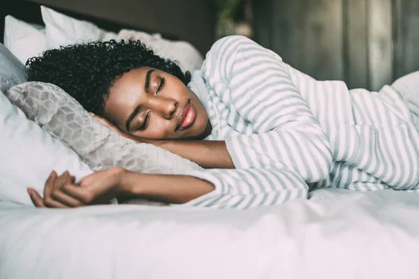 Close up de uma mulher negra bonita com cabelo encaracolado dormindo na cama olhos fechados — Fotografia de Stock