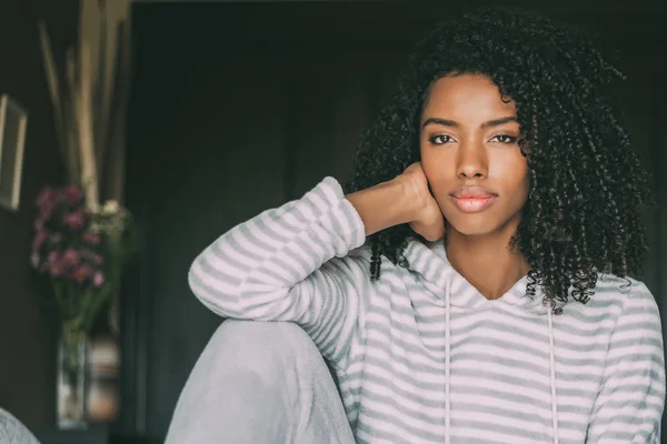 Hermosa mujer negra pensativa sentarse en la cama mirando a la cámara — Foto de Stock