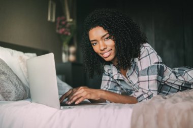güzel siyah kadın yatakta dizüstü bilgisayar ve kahve