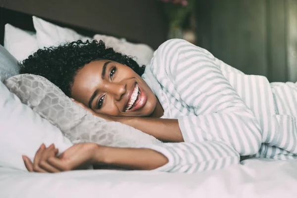 Κοντινό πλάνο του μια όμορφη μαύρη γυναίκα με σγουρά μαλλιά χαμογελώντας και ξαπλωμένος στο κρεβάτι, βλέπουν τα φωτογραφικών μηχανών — Φωτογραφία Αρχείου
