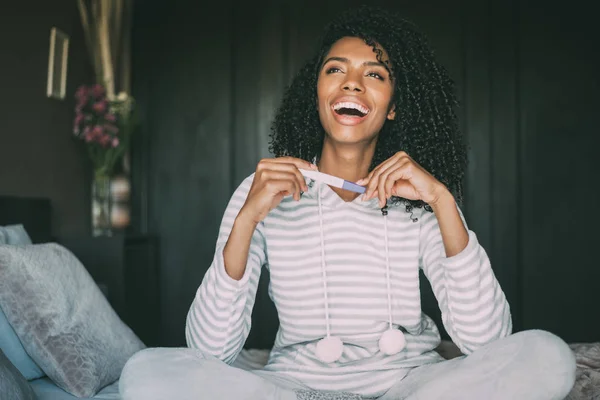 Ευτυχισμένη μαύρη γυναίκα με ένα τεστ εγκυμοσύνης στο κρεβάτι — Φωτογραφία Αρχείου