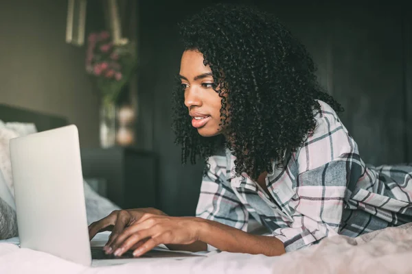 beautiful black woman on bed with laptop and cup of coffee