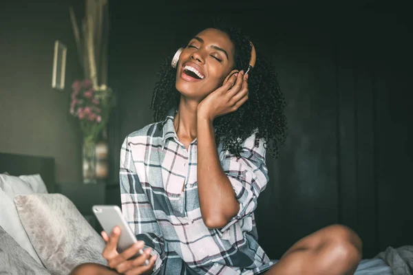 woman on bed listening music with headphones and smartphone